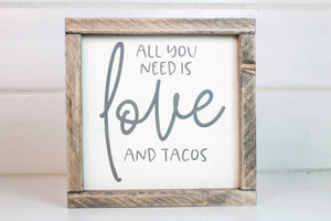 Wood framed sign featuring the saying, "All you need is love and tacos." Frame is stained in Classic Gray finish. Sign is cream with gray vinyl lettering