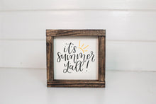 Load image into Gallery viewer, Wood framed sign featuring the saying, &quot;It&#39;s summer y&#39;all.&quot; Frame is stained espresso and sign is a cream background with black lettering and a yellow sun accent